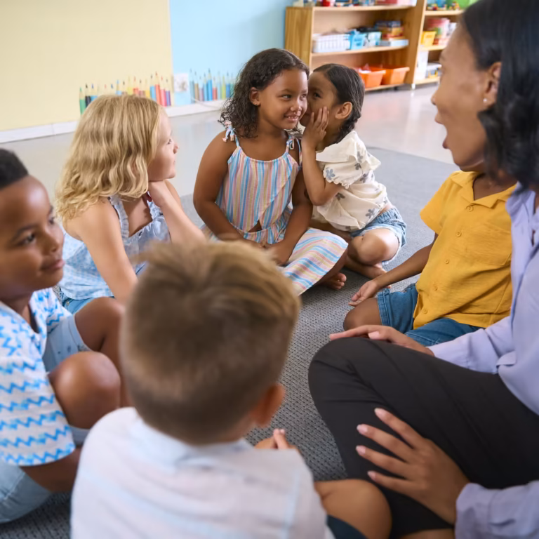Teacher and a diverse group of young children sitting together on the classroom floor