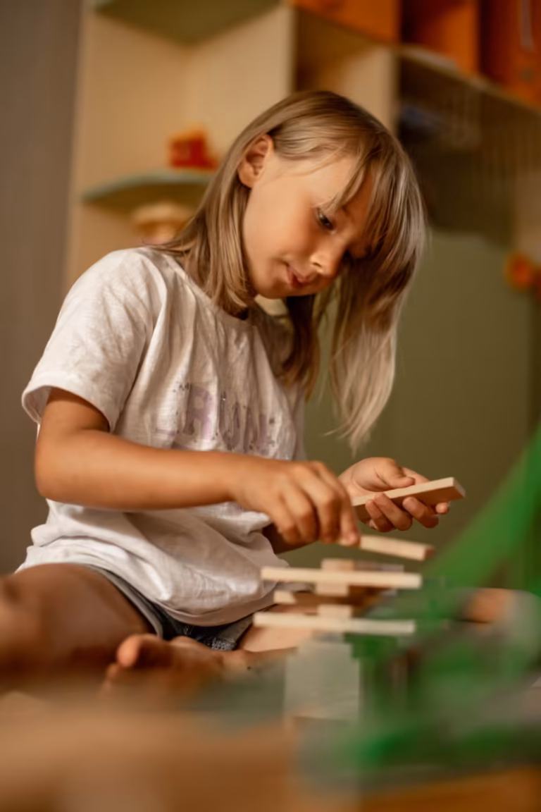 Young girl concentrating as she carefully stacks wooden blocks