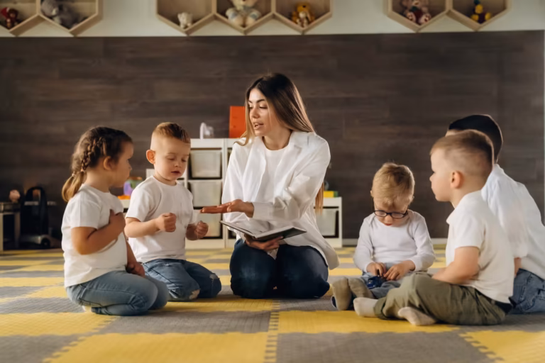 Educator reading a storybook to a small group of young children on the classroom floor