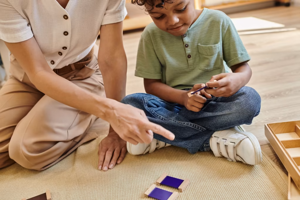 Teacher sitting on the classroom floor working one-on-one with a child