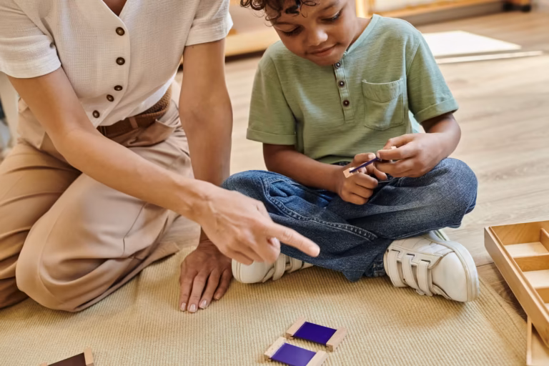 Teacher sitting on the classroom floor working one-on-one with a child