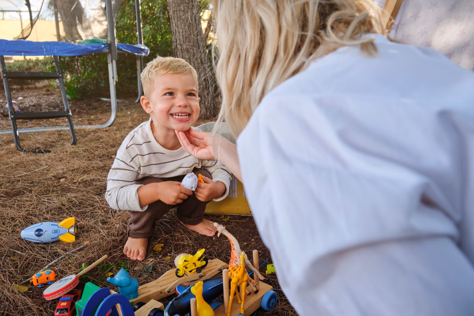 Happy child playing with toys near their mother in a park
